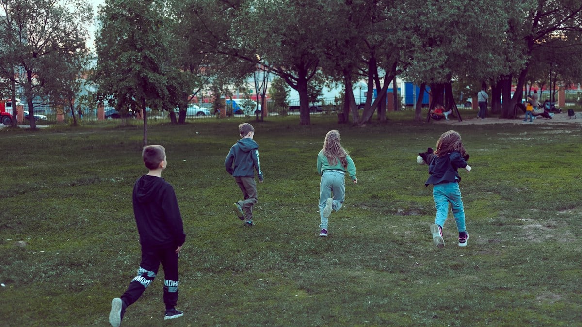 Children run on the field in the park, funny kids play, run after each other.